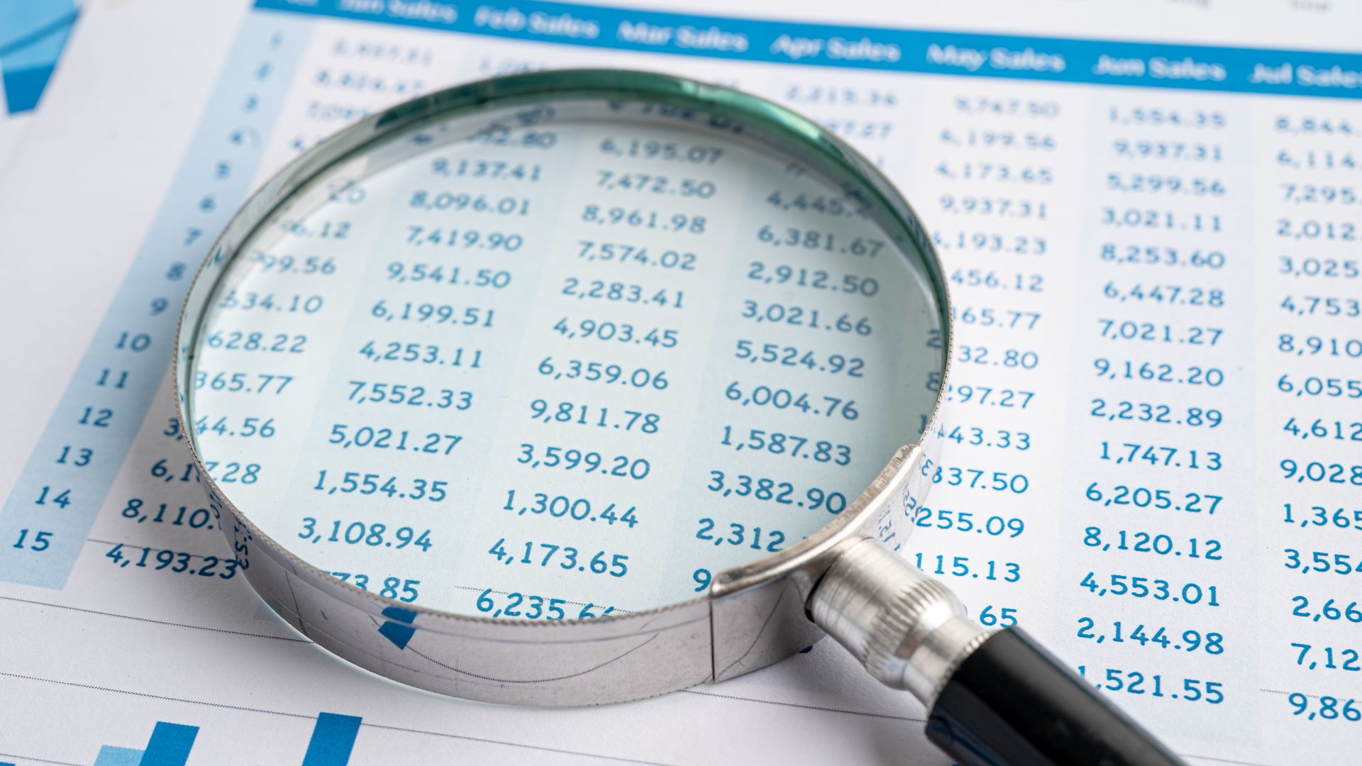 financial spreadsheet under a magnifying glass
